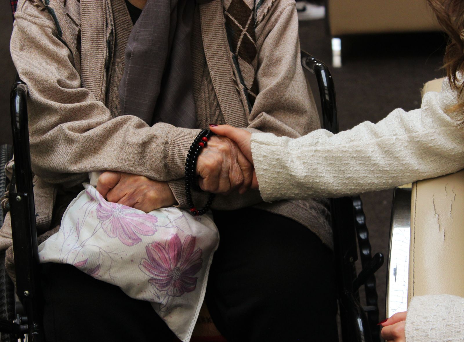 A caregiver gently holding an older adult’s hand